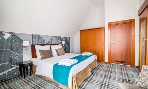 Stylowy pokój double z podwójnym łóżkiem z gdańską fototapetą na ścianie i eleganckimi szafami