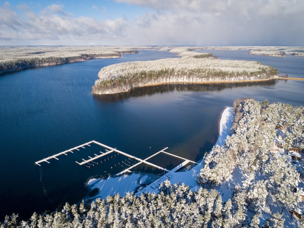 Jezioro Wdzydze zimą z lotu ptaka - ośnieżony las, wyspa i pomosty mariny Largo