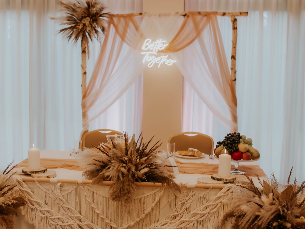 Stół pary młodej z dekoracją boho i neonem Better Together
