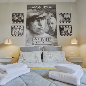 Wygodne łóżko z plakatami filmowymi nad nim – połączenie komfortu i pasji do kina.