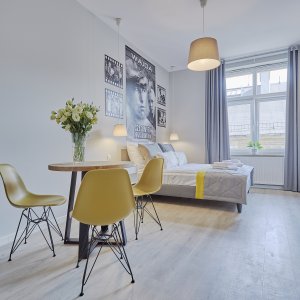 Rzut na przestronną sypialnię z dużym łóżkiem i świeżymi kwiatami na stole – elegancka i przytulna aranżacja.