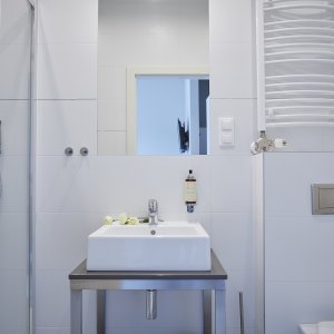 Elegancka, prosta umywalka w apartamencie z prywatną łazienką, harmonizująca z nowoczesnym wystrojem wnętrza.
