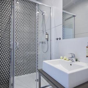 Nowoczesna łazienka z przestronną kabiną prysznicową, eleganckimi akcentami i funkcjonalnym wyposażeniem.