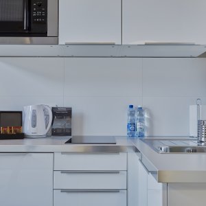 Praktycznie urządzony aneks kuchenny w apartamencie w Krakowie, z nowoczesnymi sprzętami, elegancką kuchenką i przestronnym blatem roboczym.