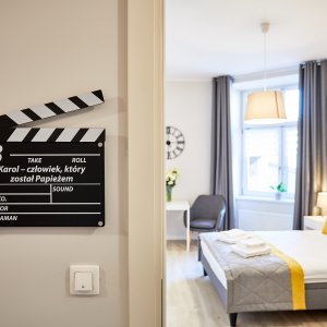 Stylowe wejście do apartamentu inspirowanego kinem, z unikalnym wystrojem i plakatami filmowymi.