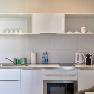 Nowoczesny aneks kuchenny w apartamencie, wyposażony w funkcjonalne sprzęty