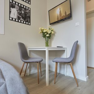 Elegancki stolik z wygodnymi krzesłami i świeżymi kwiatami, tworzący przytulną atmosferę.