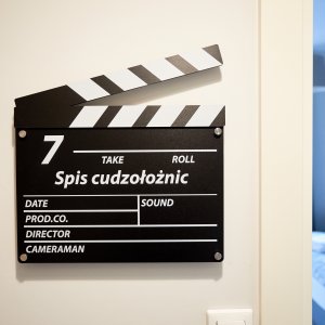 Filmowy klaps z tytułem filmu, dodający klimatu tematycznemu wnętrzu.