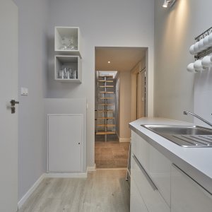 Korytarz z widocznym aneksem kuchennym w nowoczesnym apartamencie