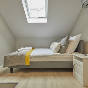  Łóżko ustawione pod skoszoną ścianą w nowoczesnym apartamencie