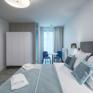 Sypialnia z prostym, ale eleganckim wystrojem, pełnym jasnych kolorów i subtelnych dodatków.