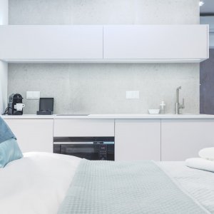 Przestronny aneks kuchenny w pełni wyposażony, z nowoczesnym blatem roboczym, sprzętem AGD i eleganckimi detalami. 