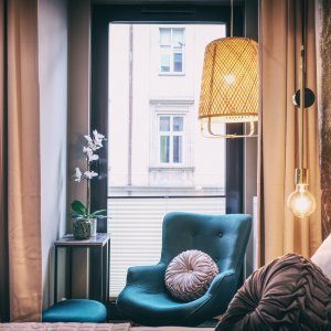  Przytulny kącik wypoczynkowy z fotelem pod dużym oknem i nastrojowym światłem.