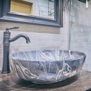 Designerska umywalka z nowoczesną armaturą w eleganckiej, prywatnej łazience.