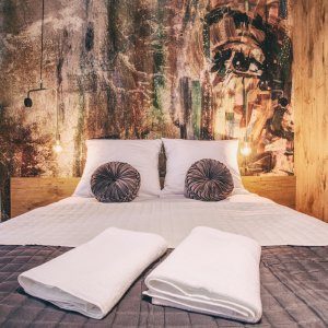 Starannie pościelone łóżko z jasną pościelą w minimalistycznej aranżacji sypialni.