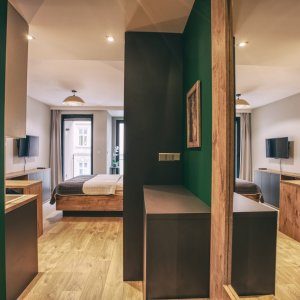 Naturalny wystrój wnętrza z elementami drewna i butelkową zielenią w detalach.