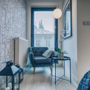 Przytulny kącik z miękkim fotelem i lampą, idealny do relaksu przy oknie.