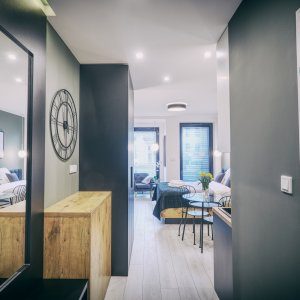 Widok na wejście do apartamentu przez jasny, niebiesko-biały korytarz.