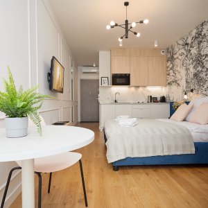 Nocleg w przestronnej przestrzeni z elegancką tapetą, drewnianymi akcentami i subtelnymi niebieskimi detalami, zapewniający komfortowy pobyt w centrum Krakowa.
