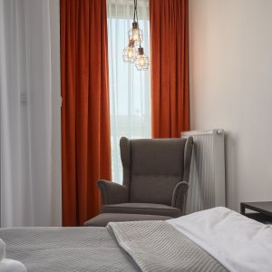 Przytulny kącik z eleganckim fotelem uszakiem w apartamencie na wynajem w Krakowie.