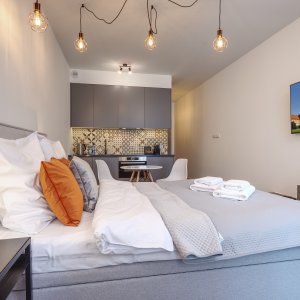 Przytulna sypialnia z dużym łóżkiem, telewizorem i ciepłym oświetleniem, idealna na wieczorny relaks.