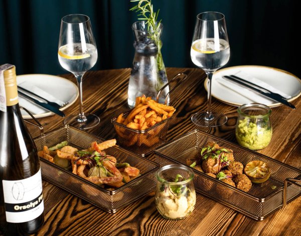 Lunch dnia w Krakowie – różnorodne dania serwowane dla dwóch osób, z kieliszkiem dobrego wina, w eleganckim wnętrzu restauracji.