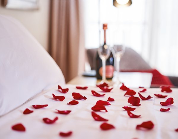 płatki róż w na hotelowym łóżku