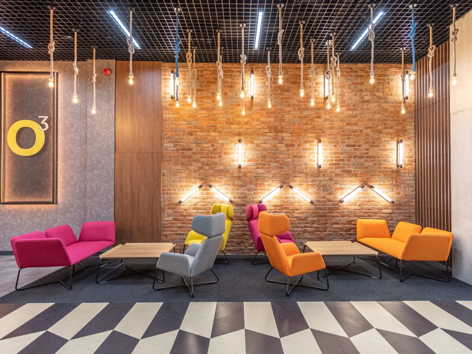 Strefa wypoczynkowa w o3Hotel — ceglana ściana, industrialne żarówki i kolorowe fotele